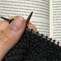 Someone knitting in front of a book
